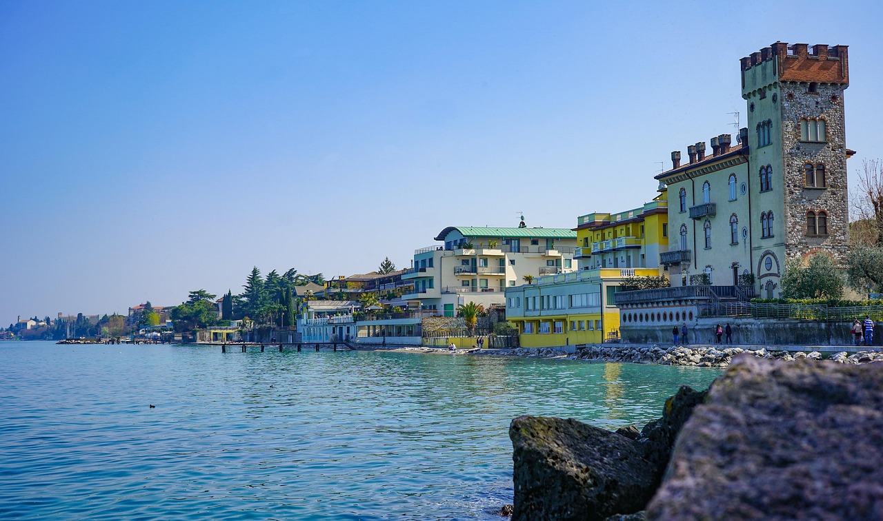 Spiaggia affollata sul Lago di Garda, con persone che si godono il sole e il panorama, a pochi passi da Brescia.