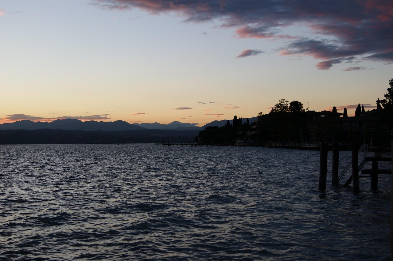 Escursionisti ammirano il tramonto sul Lago di Garda, con panorami mozzafiato e colori vibranti nel cielo.