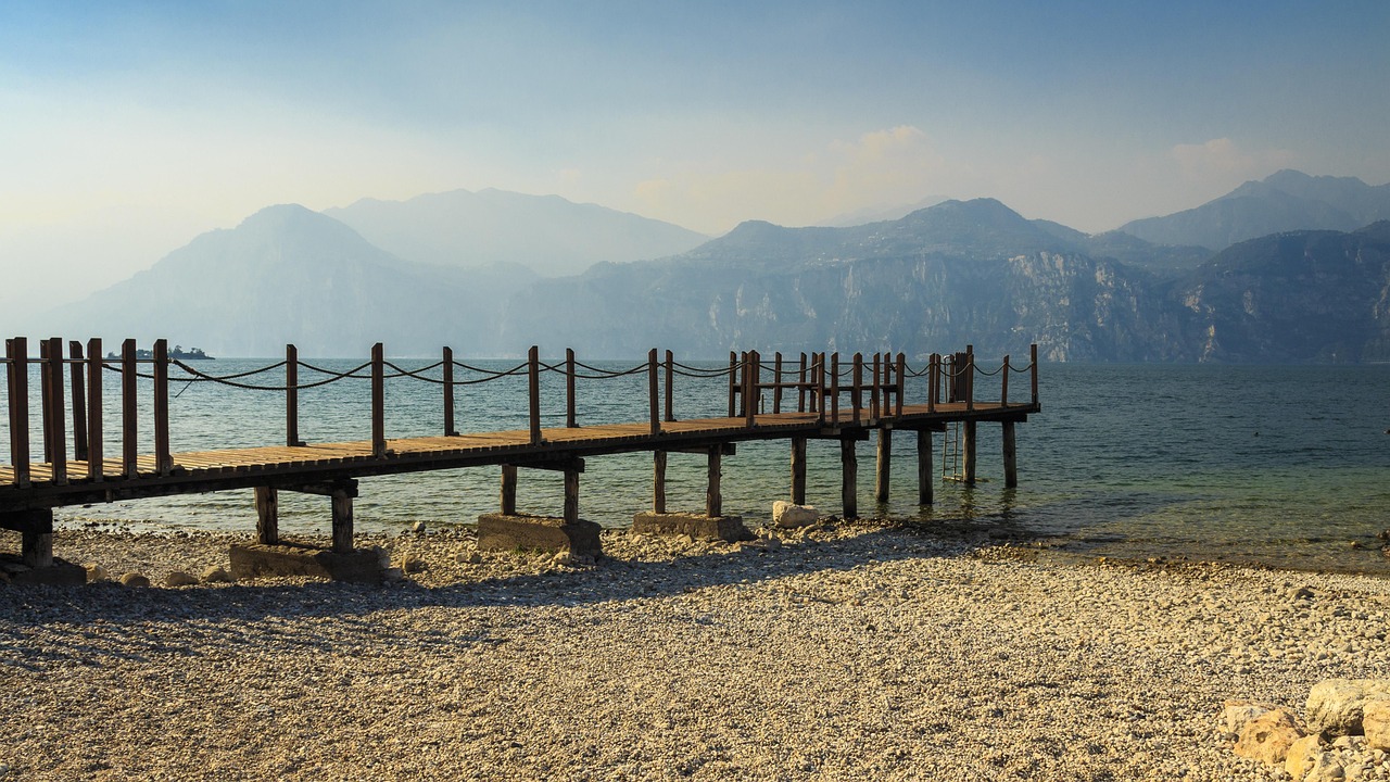 Spiaggia del Lago d'Iseo con persone che prendono il sole e nuotano in acque cristalline.