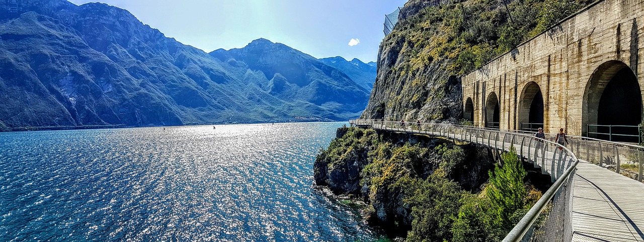 Ciclista su una pista ciclabile panoramica attorno al Lago d'Iseo, con vista mozzafiato sulle montagne.