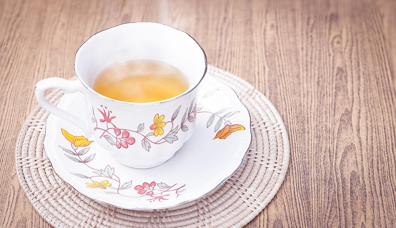Tazza di tè tiepido con foglie di tè e limone, simbolo di benessere e perdita di grasso addominale.