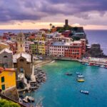 Vista panoramica di un borgo colorato sul mare in Italia, con case vivaci e acque cristalline.