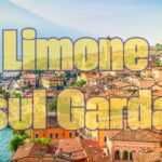 Paesaggio del Lago di Garda con un pittoresco paese affacciato sulle acque blu, circondato da colline verdi.