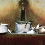 Pentola bruciata con segni di ustione e detergente per il recupero.